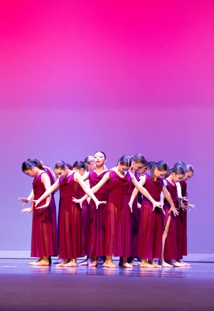 Group of lyrical dancers on stage performing at dance competition.
