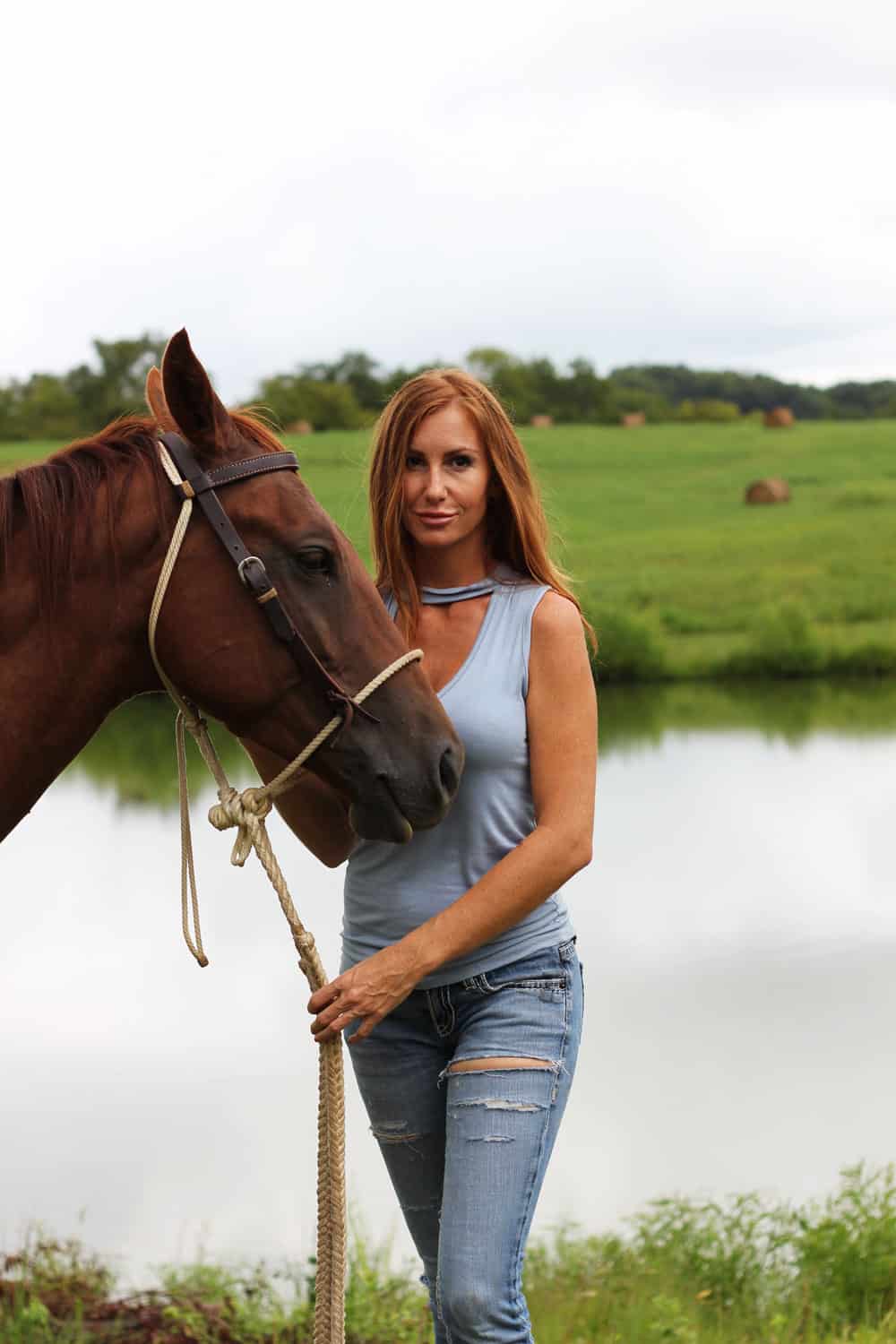 Girl holding a horse by the reins by a pond on a farm in Tennessee.